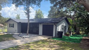 Uma casa residencial com garagem, entrada por meio de um caminho e área gramada.