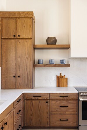 A kitchen with wooden cabinets, a marble countertop, and a built-in oven. - NEW Modern Sanctuary | Minutes to Zion Desert | Pool, Spa and Game Room (Virgin)