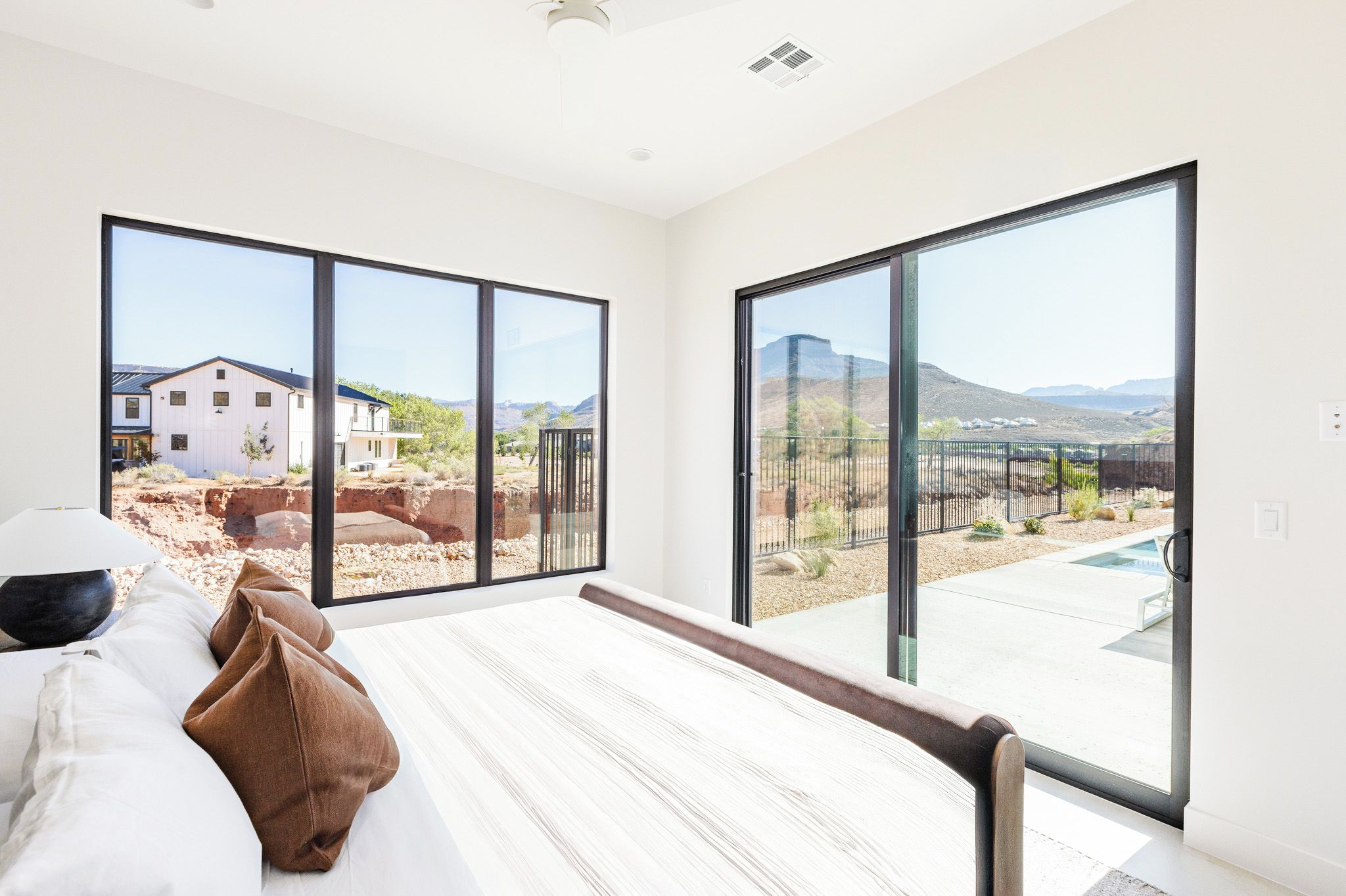 Un dormitorio con una cama grande, vistas a un paisaje desértico y una piscina exterior.