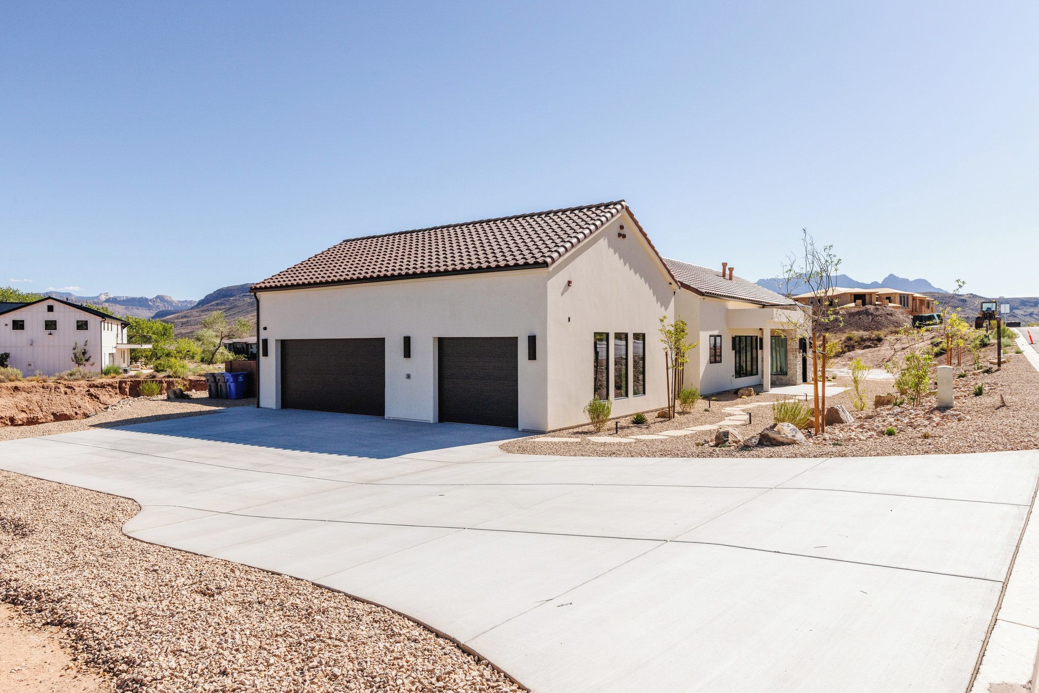 A modern two-story house with a garage, surrounded by a landscaped driveway and a desert landscape.
