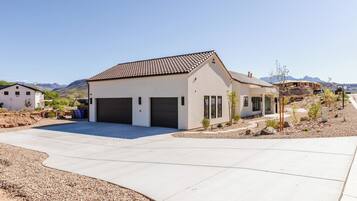 A modern two-story house with a garage, surrounded by a landscaped driveway and a desert landscape.