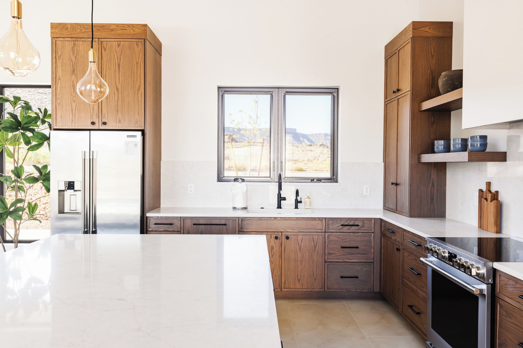 Una cocina moderna con gabinetes de madera, un refrigerador de acero inoxidable, un lavamanos doble y una isla grande.
