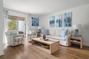 A living room with a sofa, chairs, a coffee table, and artwork on the wall. - A Place to Remember | Seabrook Convenience (Seabrook Island)