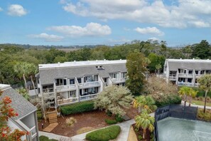 A multi-story building with balconies, surrounded by greenery and trees. - A Place to Remember | Seabrook Convenience (Seabrook Island)