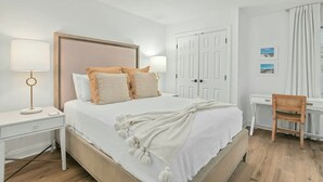 A neatly arranged bedroom with a bed, bedside tables, a desk, and a chair. - A Place to Remember | Seabrook Convenience (Seabrook Island)