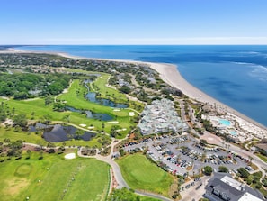 An aerial view of a coastal resort with a golf course, beachfront, and a parking area. - A Place to Remember | Seabrook Convenience (Seabrook Island)
