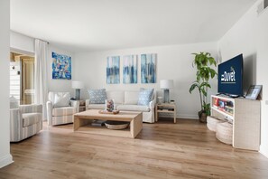 A living room with a sofa, armchairs, a coffee table, and a television. - A Place to Remember | Seabrook Convenience (Seabrook Island)