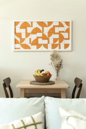 Ein Essbereich mit einem Holztisch, einer Obstschale und einer Vase mit getrockneten Blumen.