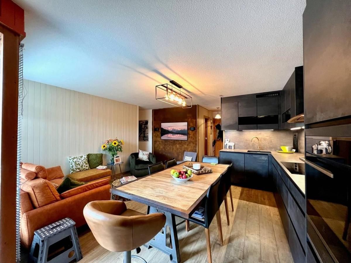 Una cocina moderna con armarios oscuros, una mesa de comedor de madera y un horno empotrado.