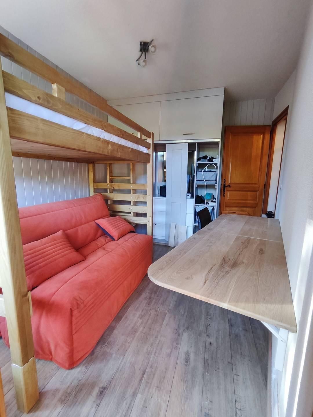 Una stanza con un letto a castello, un divano, un tavolo di legno e un'armadio.