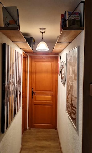 A hallway with a wooden door, framed pictures on the walls, and a pendant light fixture. - Ground floor, view ski slopes/village, terrace, tv, 51m², Les Gets (Les Gets)
