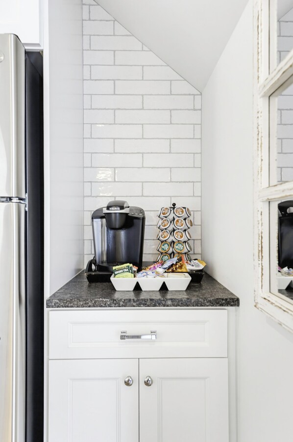A kitchen with white cabinets, a coffee maker, and a stack of coffee pods.