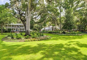 A large house with a porch, surrounded by a well-maintained lawn and various plants. - May River Cottage on Lawrence street, old Town. (Bluffton)