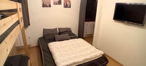 A bedroom with a bunk bed, a bed with patterned bedding, a flat-screen TV, and a radiator. - 100m from ski slopes, Ground floor, terrace, parking, tv, 34m², Les Gets (Les Gets)