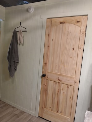 A room with a wooden door, a towel rack with a towel, and a white wall.