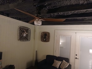 A room with a ceiling fan, a door, and a couch with patterned cushions.