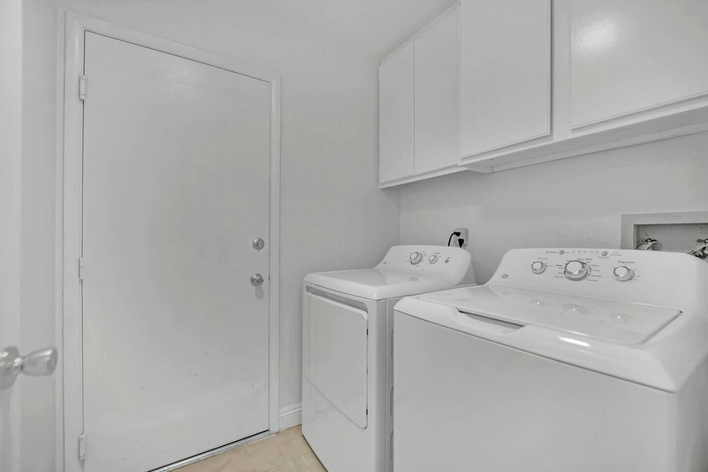 A laundry room with a closed door, a washing machine, and a dryer.