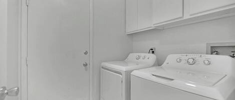 A laundry room with a closed door, a washing machine, and a dryer.