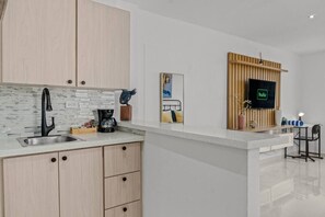 A modern kitchen with a built-in sink, a coffee maker, and a wooden cabinet. - Caribbean Sea View | Tmobile District Free Parking (SanJuan)