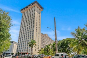 A tall hotel with multiple floors, surrounded by palm trees and parked cars. - Caribbean Sea View | Tmobile District Free Parking (SanJuan)