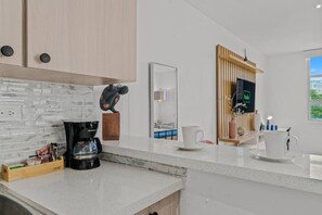Een moderne keuken met een marmeren spatwand, een koffiezetapparaat en een houten kast.
