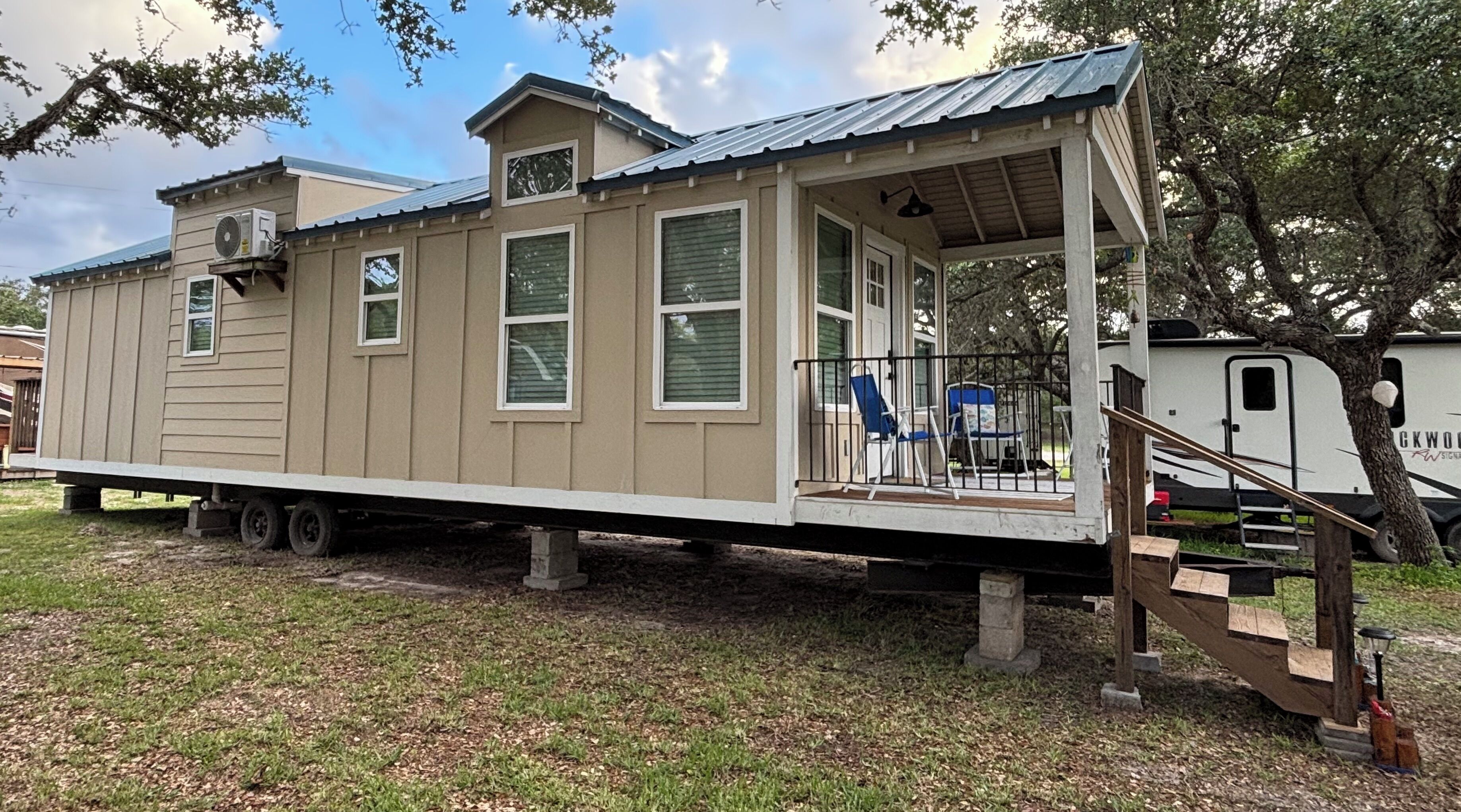 A mobile home with a porch, a small deck, and a covered outdoor area.