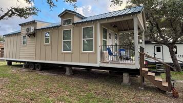 A mobile home with a porch, a small deck, and a covered outdoor area.