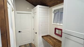 A kitchen with wooden flooring, white cabinets, and a wooden ceiling.