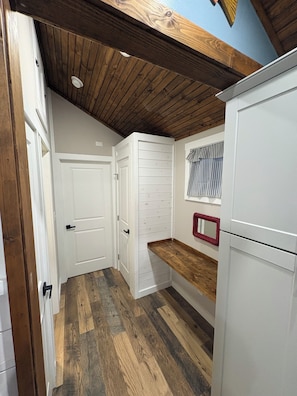 A kitchen with wooden flooring, white cabinets, and a wooden ceiling.