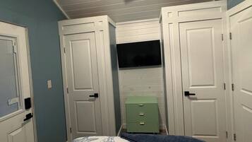 A bedroom with a ceiling fan, white doors, a green dresser, and a bed with a floral bedspread.