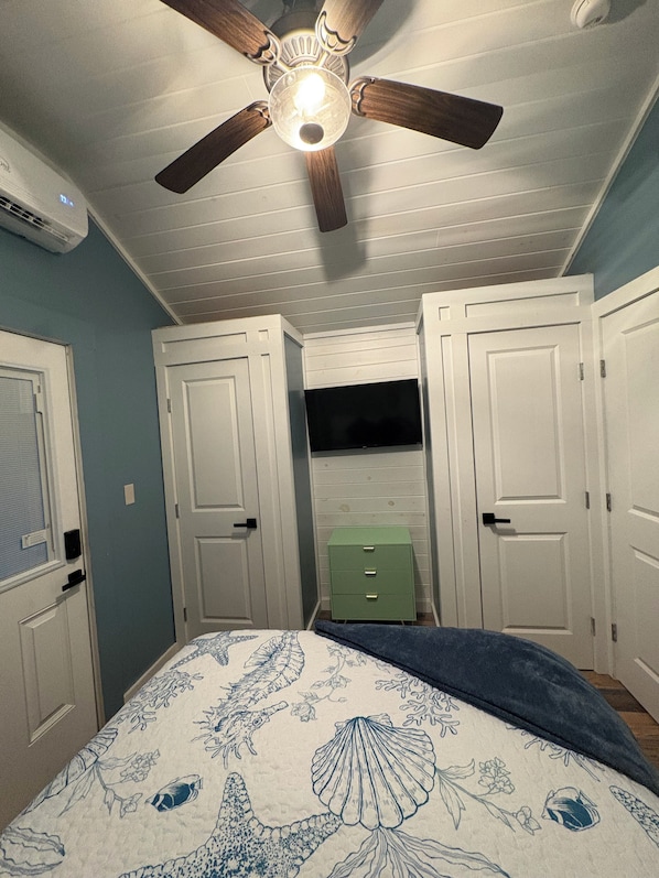 A bedroom with a ceiling fan, white doors, a green dresser, and a bed with a floral bedspread.