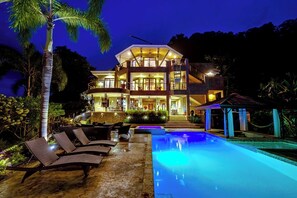 Um hotel com vários andares, piscina, área de estar externa e entrada bem iluminada.