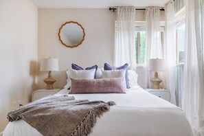 A bedroom with a bed, two bedside tables, a mirror, and curtains. - Coastal retreat with game room, hot tub & more (Bodega Bay)