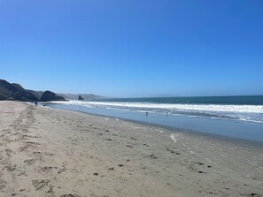 A beach with a clear sky, sandy shore, and rocky cliffs in the background. - Coastal retreat with game room, hot tub & more (Bodega Bay)