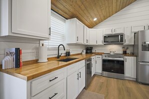 Eine moderne Küche mit weißen Schränken, einer Holz Arbeitsplatte, einem Edelstahl-Kühlschrank und einem eingebauten Backofen.