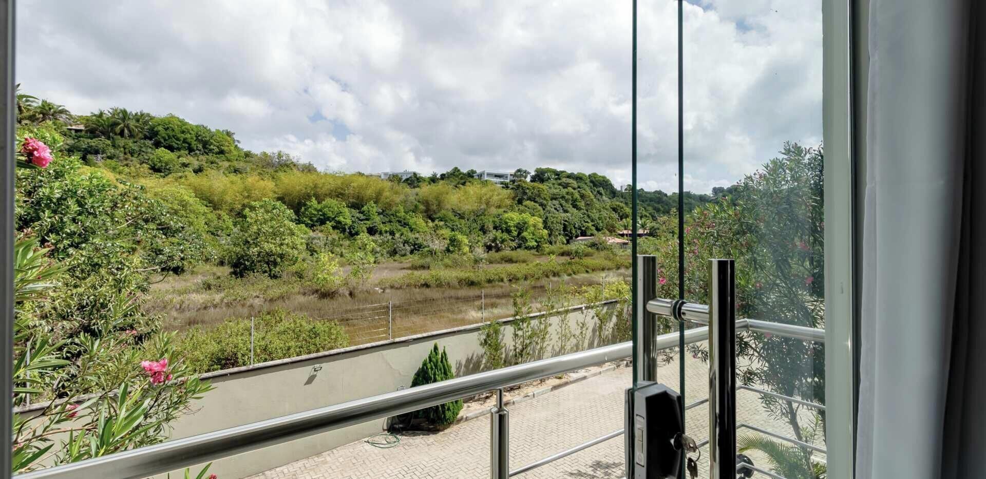 A balcony with a view of a river and surrounding greenery.