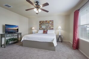 A bedroom with a bed, ceiling fan, TV, decorative mirror, bedside lamps, and a window with curtains. - Family Time - 12 min. to Downtown & The Riverwalk (San Antonio)