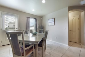 Un coin repas avec une table et des chaises, une fenêtre avec des stores et une porte.
