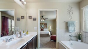 Casa de banho com duas pias, uma banheira, um ventilador de teto e um espelho.