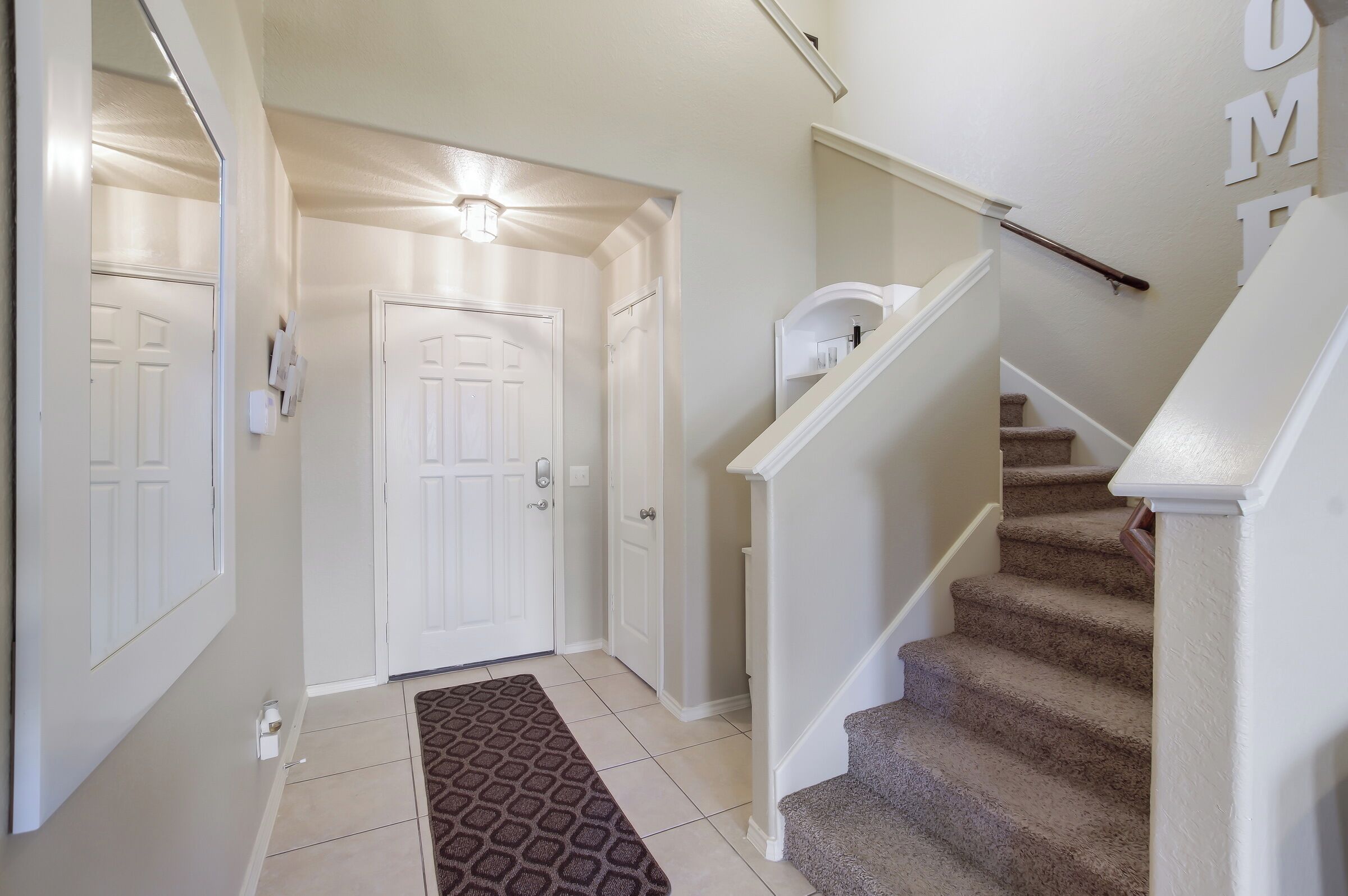 A clean, modern hallway with a carpeted staircase leading to a landing.