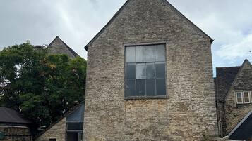 A stone building with a large window, a door, and a gravel driveway.