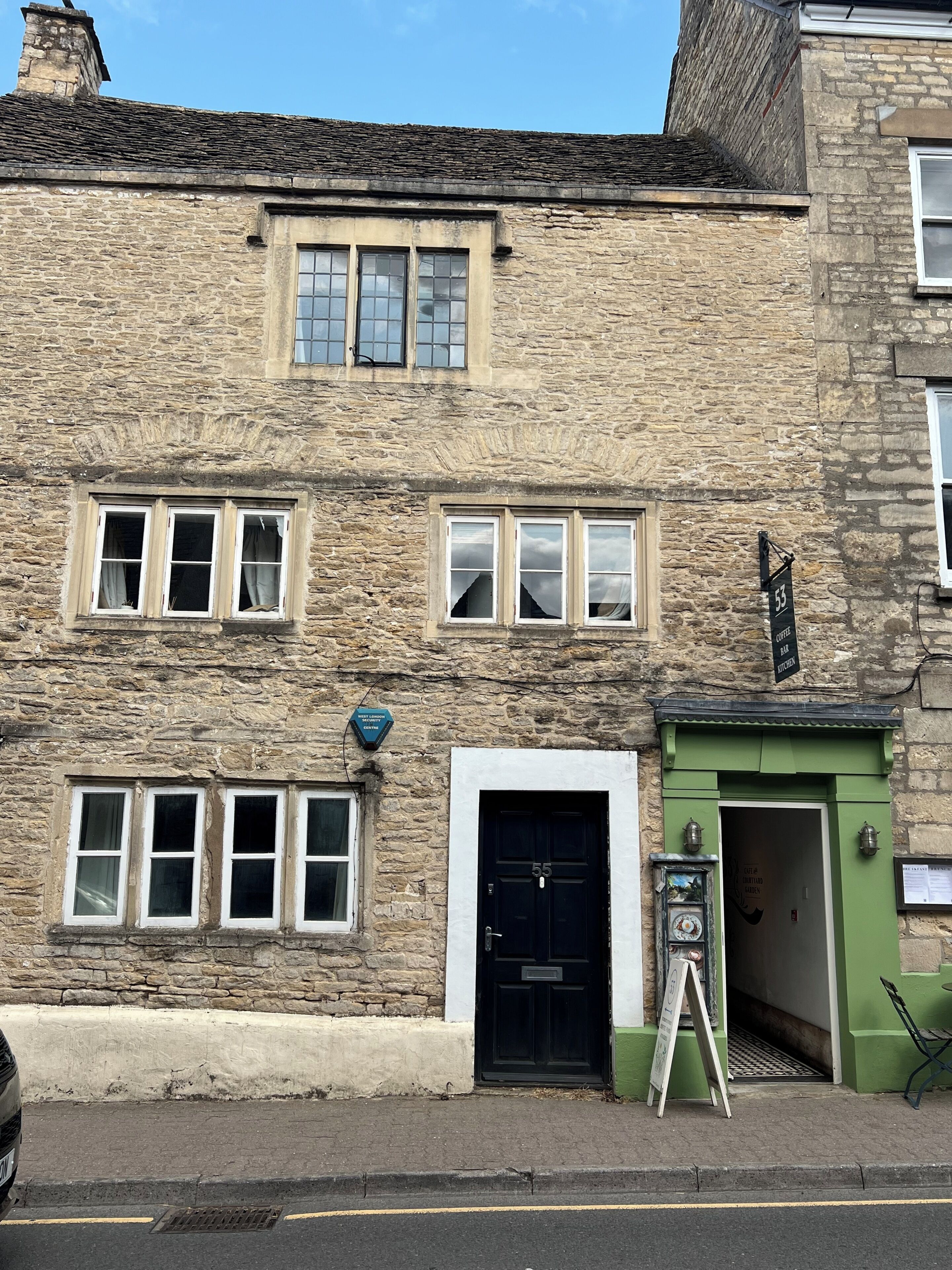 A stone building with multiple windows, a black door, and a green awning.