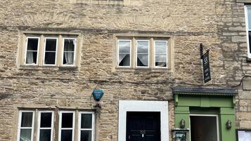 A stone building with multiple windows, a black door, and a green awning.