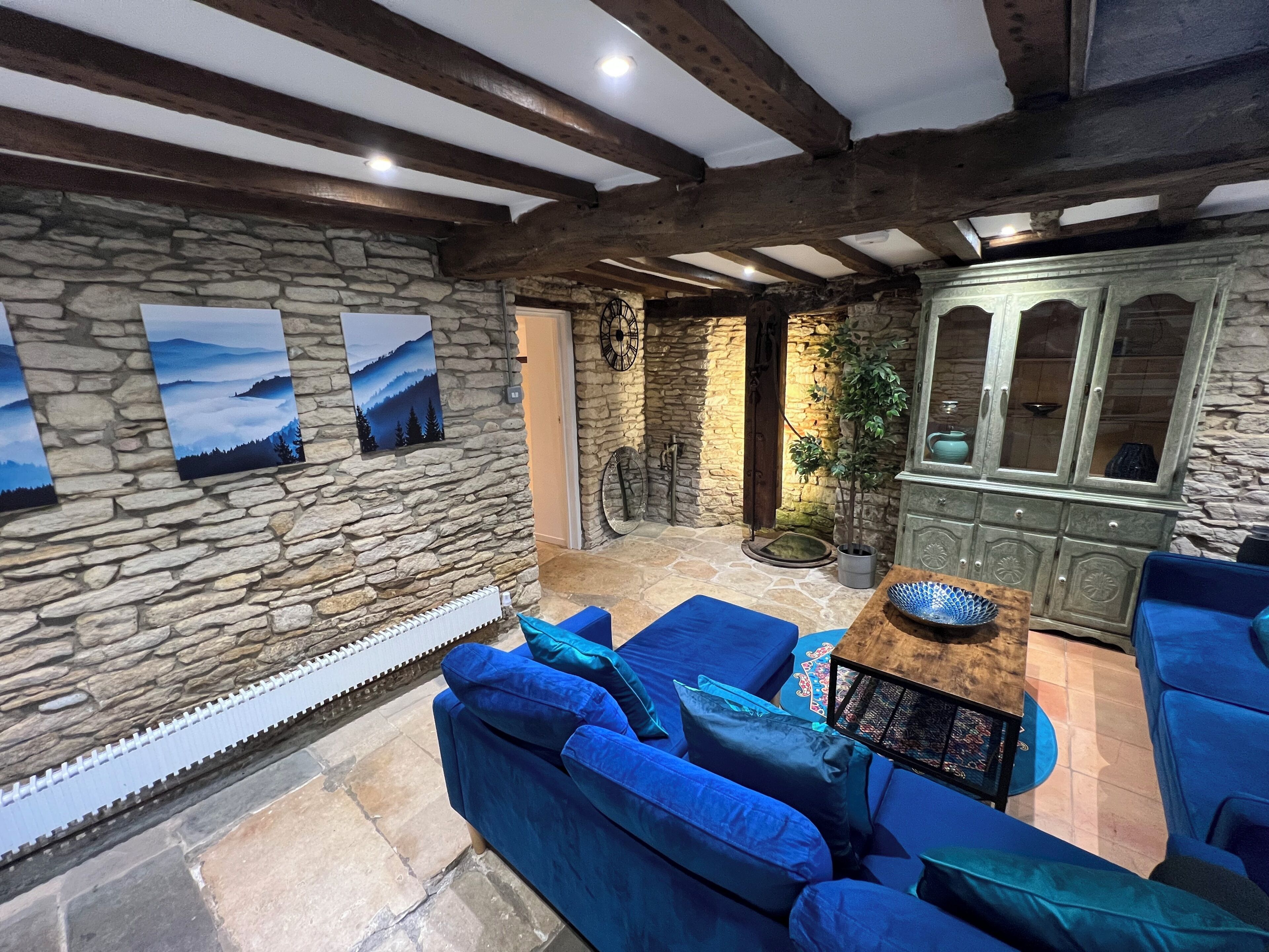 A stone-walled room with a blue sofa, a cabinet, and a view of the outdoors.