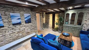 A stone-walled room with a blue sofa, a cabinet, and a view of the outdoors.