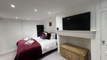 Un dormitorio con cama, televisor sobre la chimenea y una puerta.