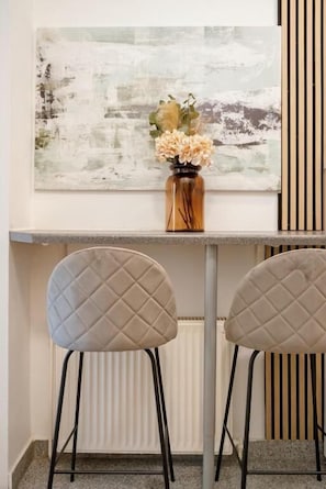 A room with a white abstract painting, a vase with flowers, and two cushioned chairs. - An der Donau und 15 Minuten ins Zentrum (Wien)