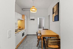 A compact kitchen with a dining area, a hanging light fixture, and a wall-mounted artwork. - An der Donau und 15 Minuten ins Zentrum (Wien)