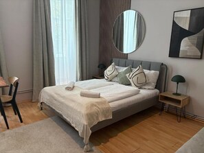 A modern bedroom with a bed, bedside tables, a chair, a mirror, and a painting on the wall. - An der Donau und 15 Minuten ins Zentrum (Wien)
