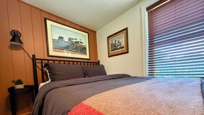 A bedroom with a bed, a nightstand, a lamp, and two framed pictures on the wall.